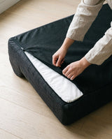 Hands operating the underside zipper of the charcoal cover.